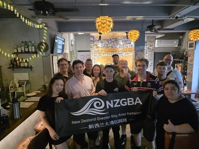 Kiwis and friends with an NZGBA banner at a community gathering