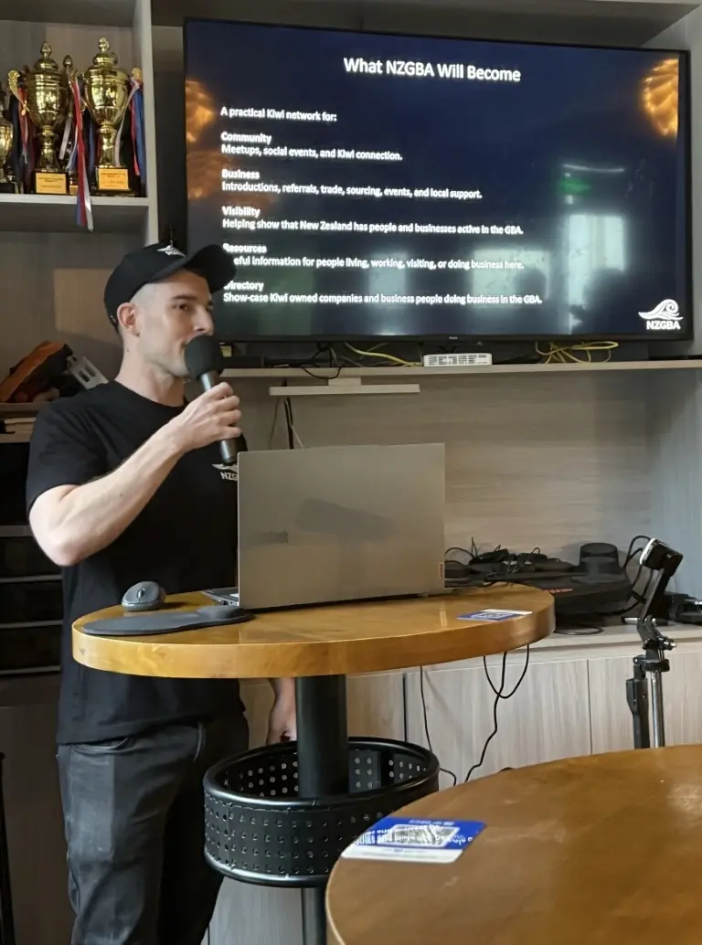 Speaker presenting NZGBA plans beside a screen