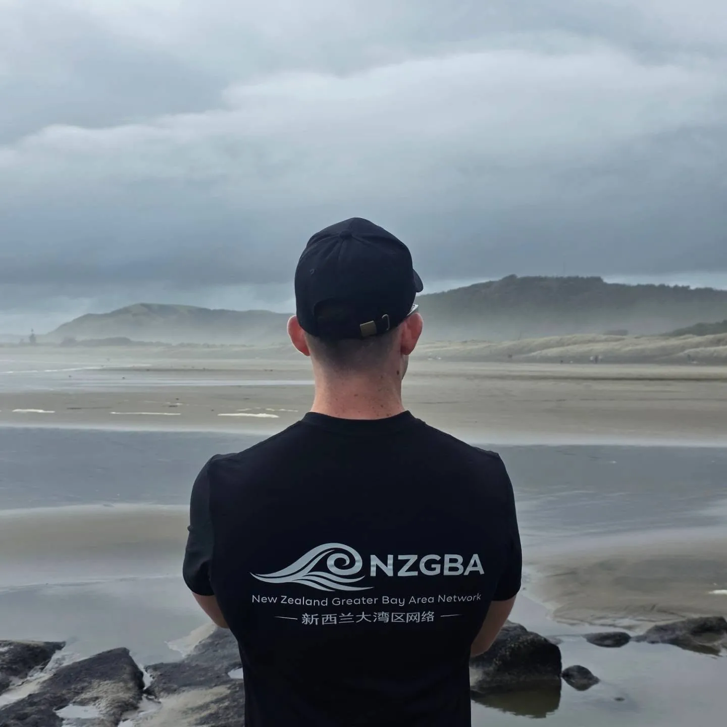 Person wearing an NZGBA shirt looking towards a beach